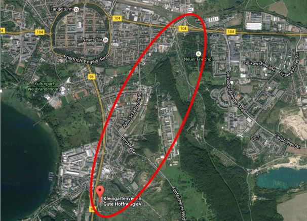 Luftbild einer Stadt, Straße und Gebäuden innerhalb eines roten Ovals.