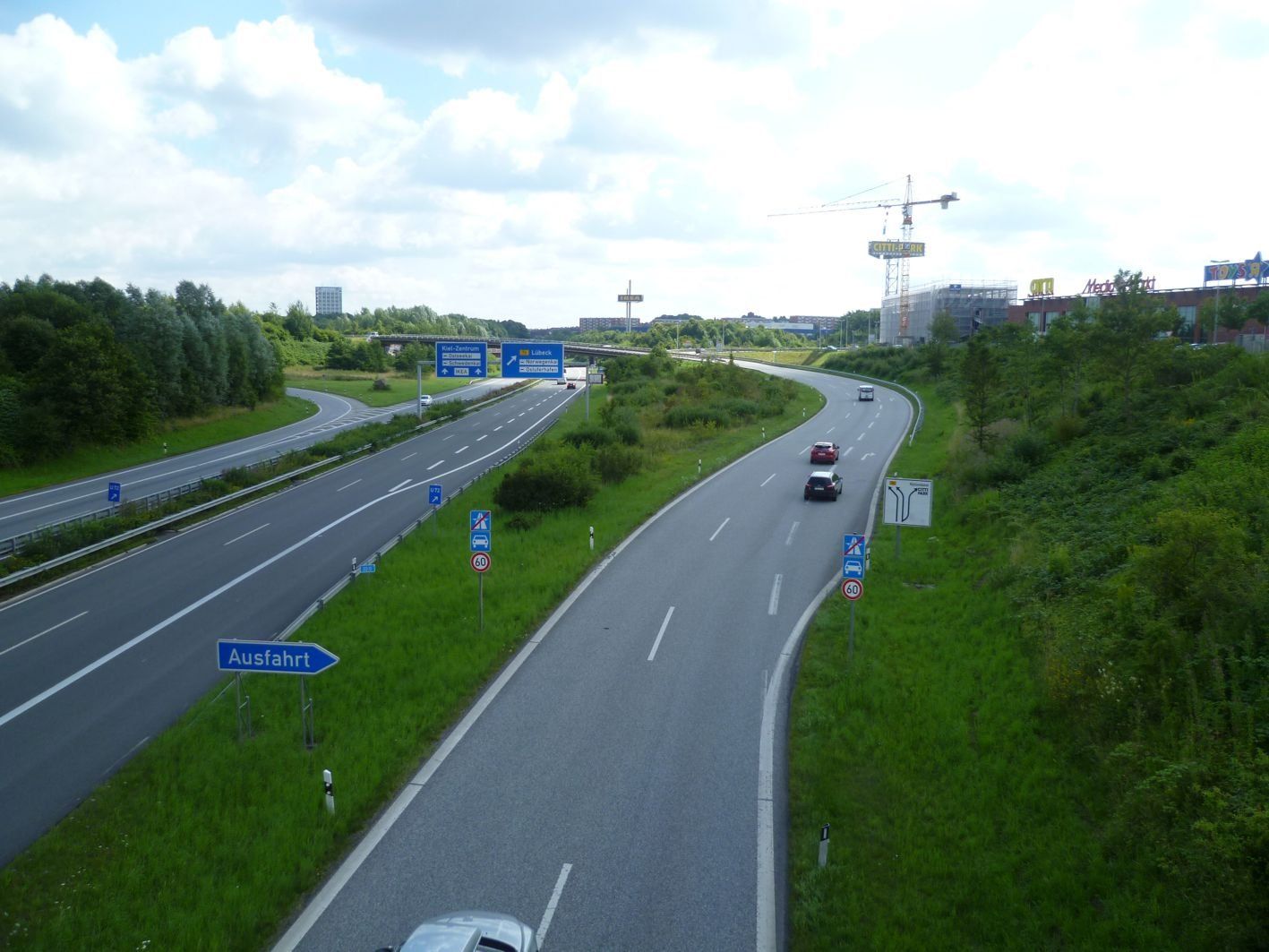 Autobahn mit zwei Fahrspuren und Einfädelungsrampe, Schild „Einfahrt“, grasbewachsene Böschungen.