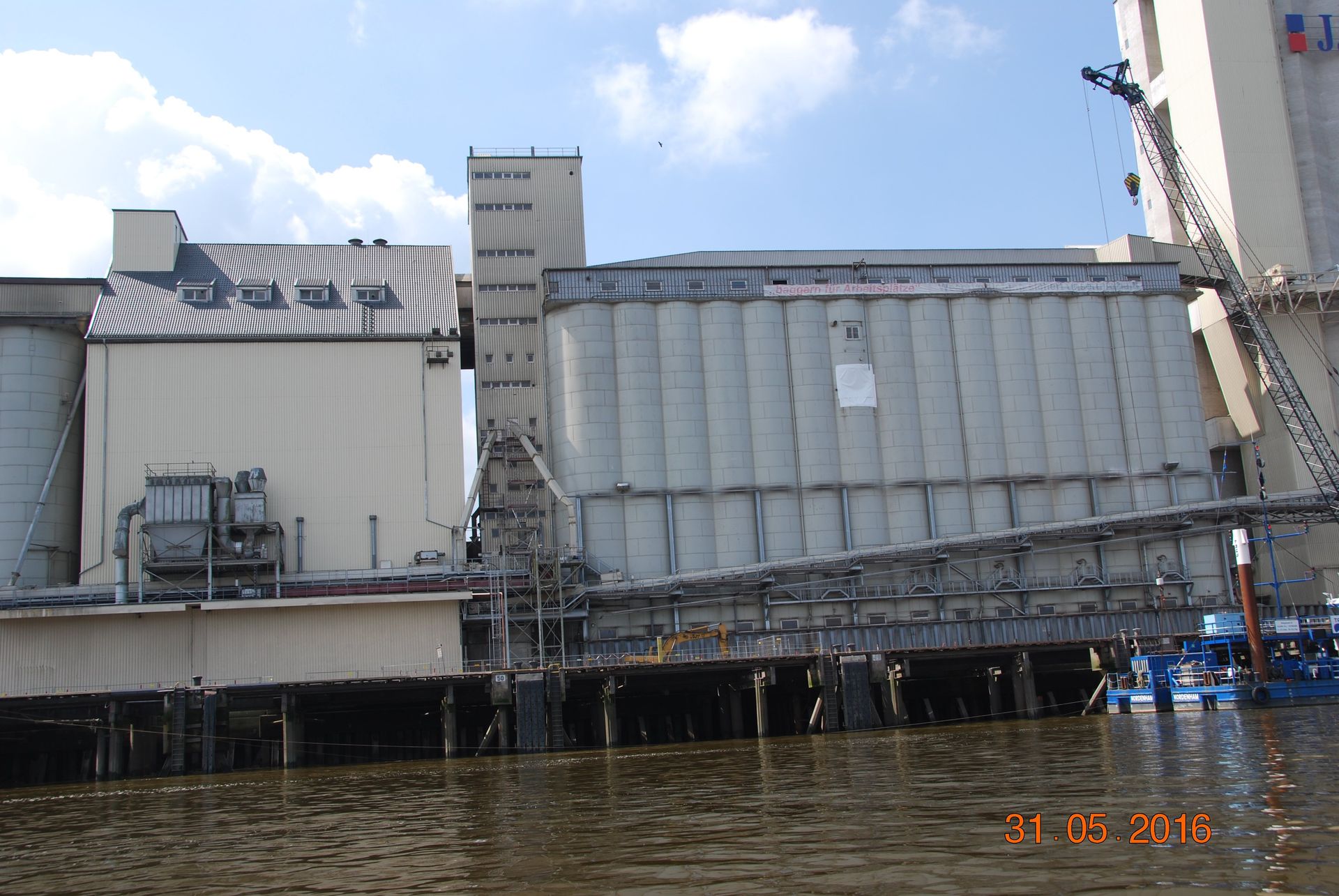 Gebäude am Wasser mit Förderanlagen; Industriegelände.