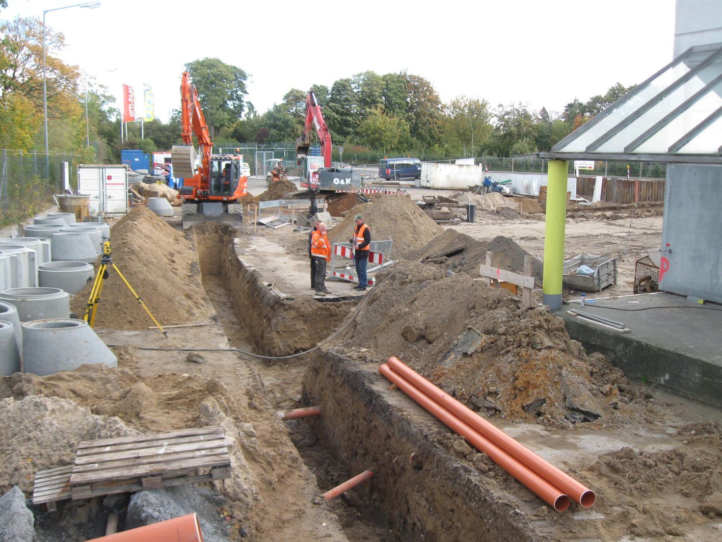 Baustelle mit Baggern, Arbeitern in Sicherheitswesten und Gräben.