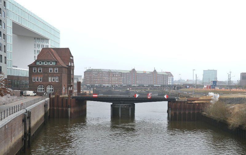 Eine niedrige Brücke über das Wasser in Hamburg, Deutschland, mit Gebäuden auf beiden Seiten. Bewölkter Himmel.