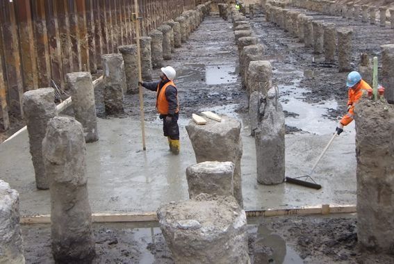 Bauarbeiter gießen Beton um Betonpfeiler auf einer Baustelle.