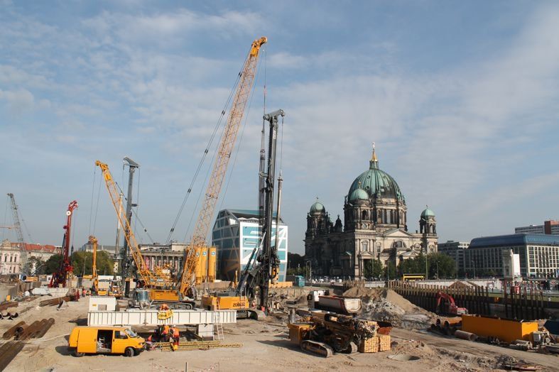 Baustelle mit Kränen und schwerem Gerät vor dem Berliner Dom unter bewölktem Himmel.