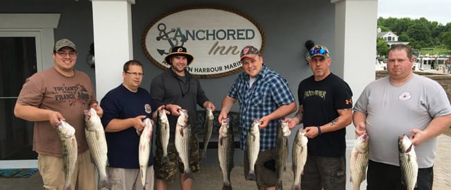 Men standing in front of Anchored Inn holding rock fish