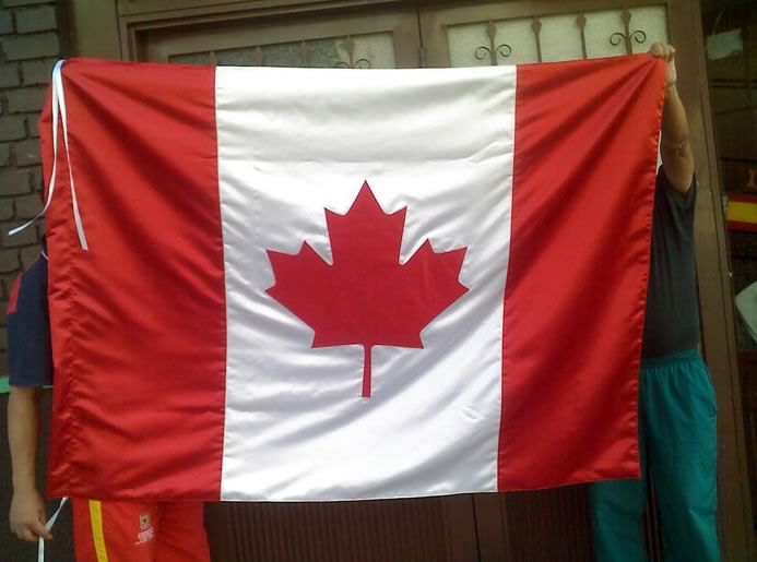 Bandera canadiense con paneles laterales rojos y una hoja de arce roja sobre un centro blanco, sostenida en el interior.