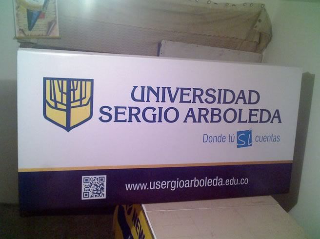 Letrero de la Universidad Sergio Arboleda con logotipo, código QR y sitio web en una pizarra blanca y morada.
