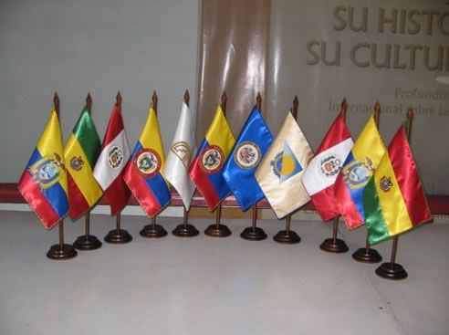 Banderas nacionales en miniatura sobre bases negras dispuestas en fila sobre una mesa.