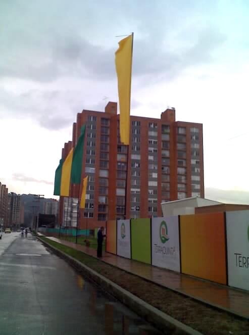 Calle mojada junto a un edificio de apartamentos de ladrillo rojo con altas pancartas amarillas 
