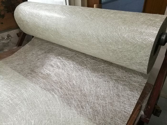 Fiberglass chop strand mat roll on the table is in process for prepare raw material in FRP production