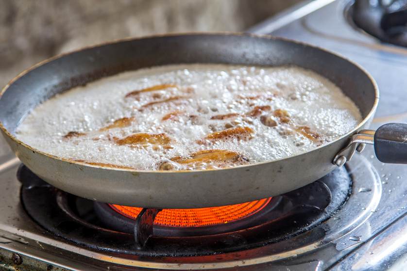 A frying pan is cooking on a gas stove.