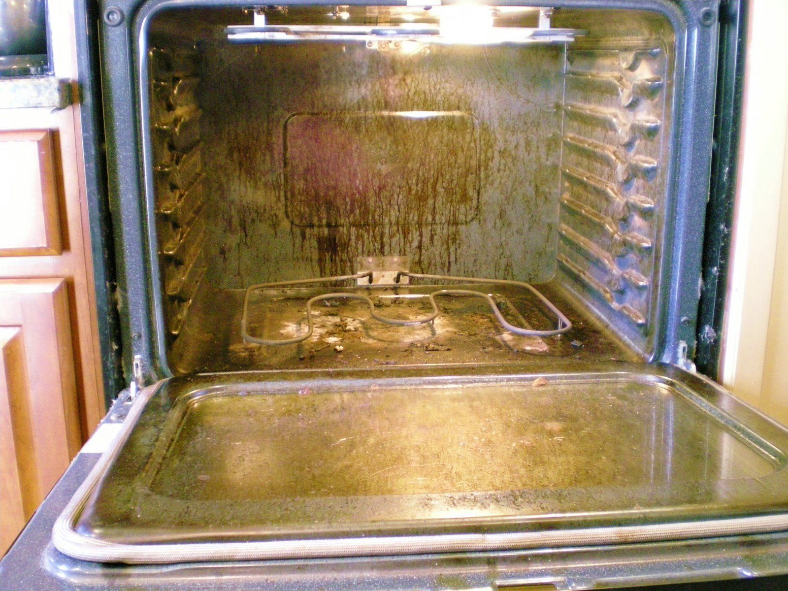 The inside of a dirty oven with the door open. Total Clean Oven Cleaning.
