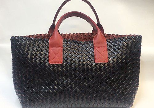una borsa di pelle intrecciata di color nero e marrone