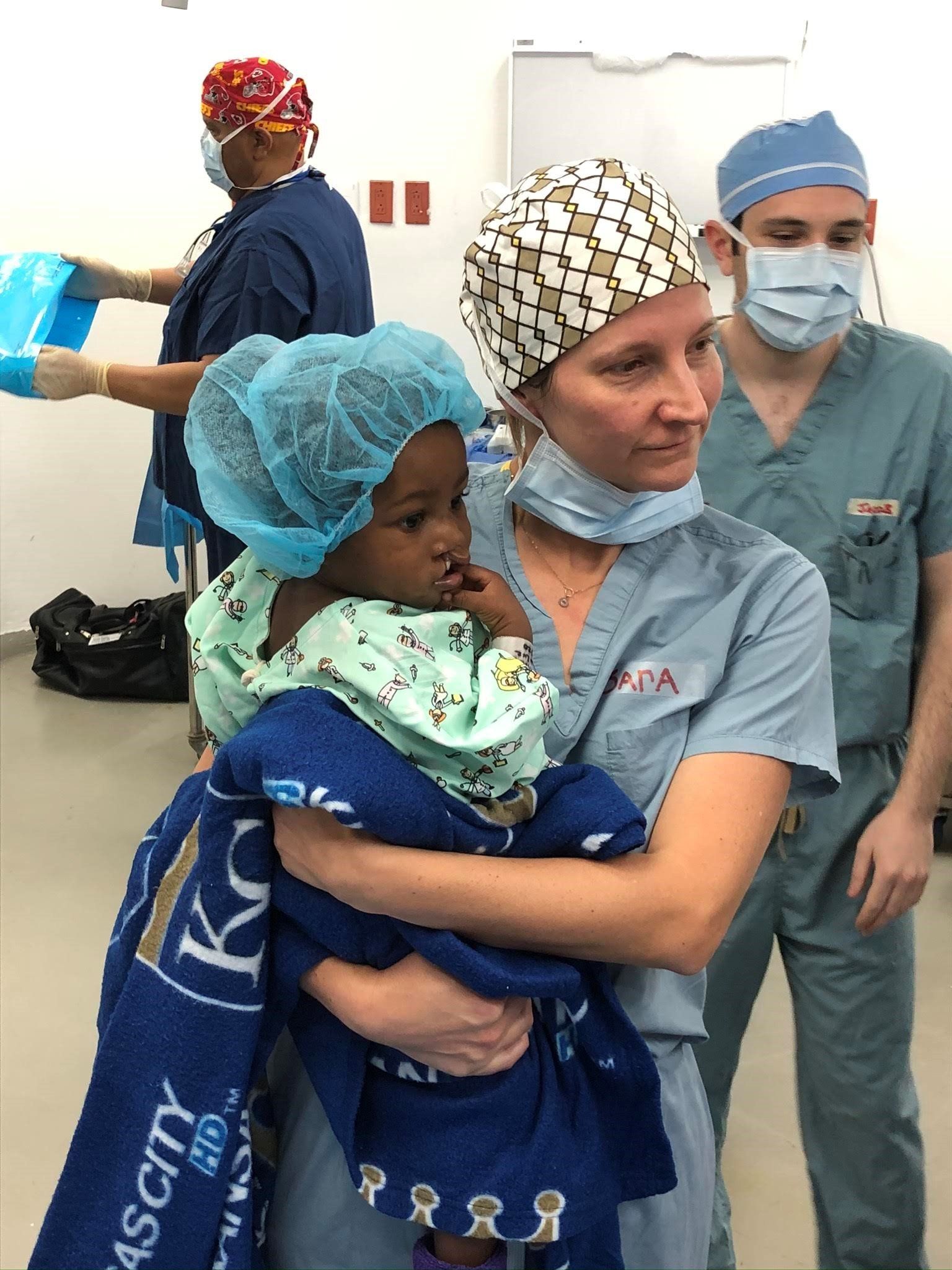 A nurse is holding a baby in her arms in an operating room.