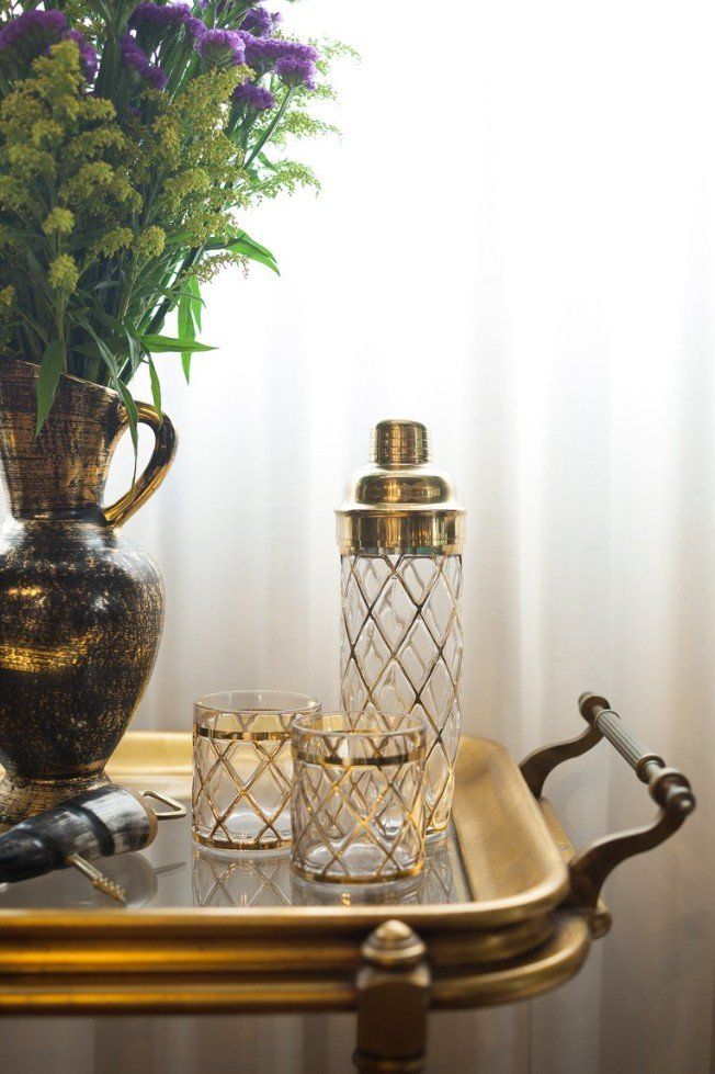 A bar cart with a vase of flowers and glasses on it.