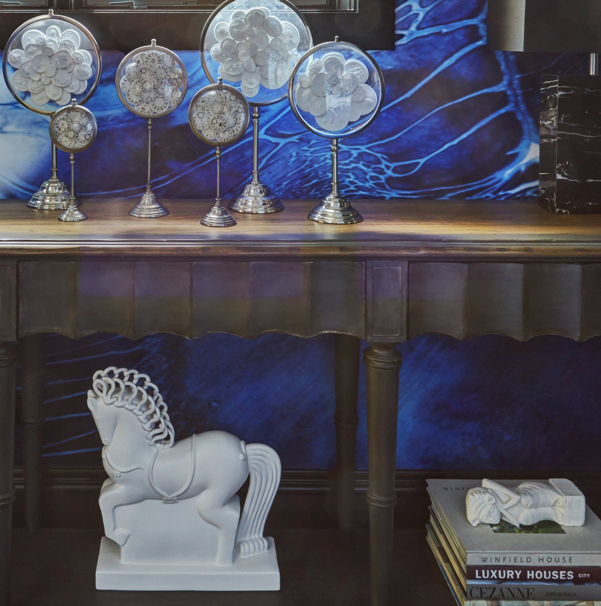 A statue of a horse sits on a table next to a stack of books
