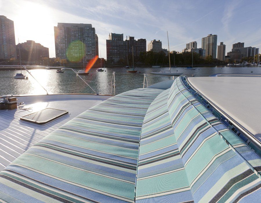 A striped cushion on the deck of a boat with a city in the background
