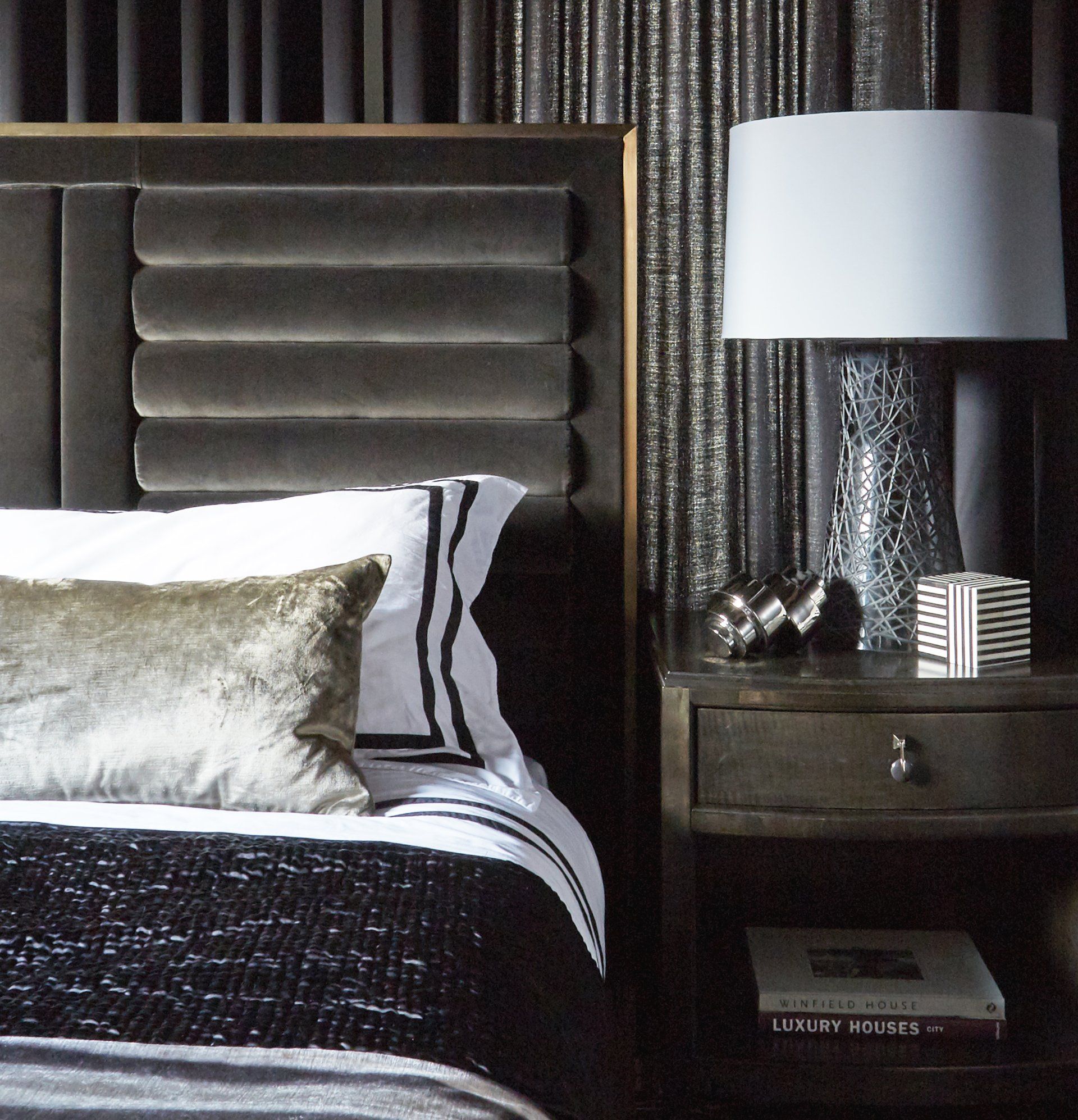 A bedroom with a bed a nightstand and a lamp