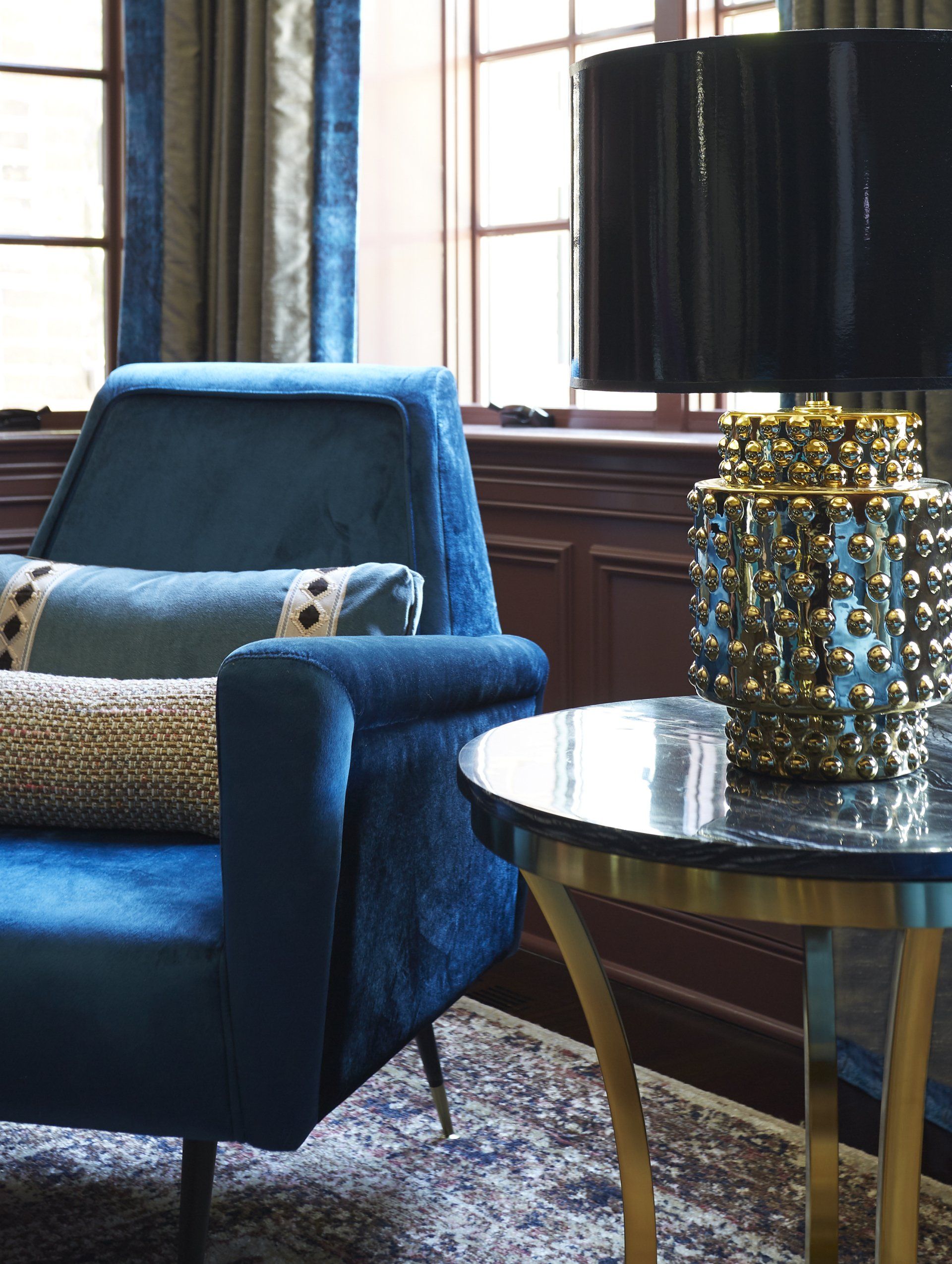 A blue chair is sitting next to a table and a lamp in a living room.