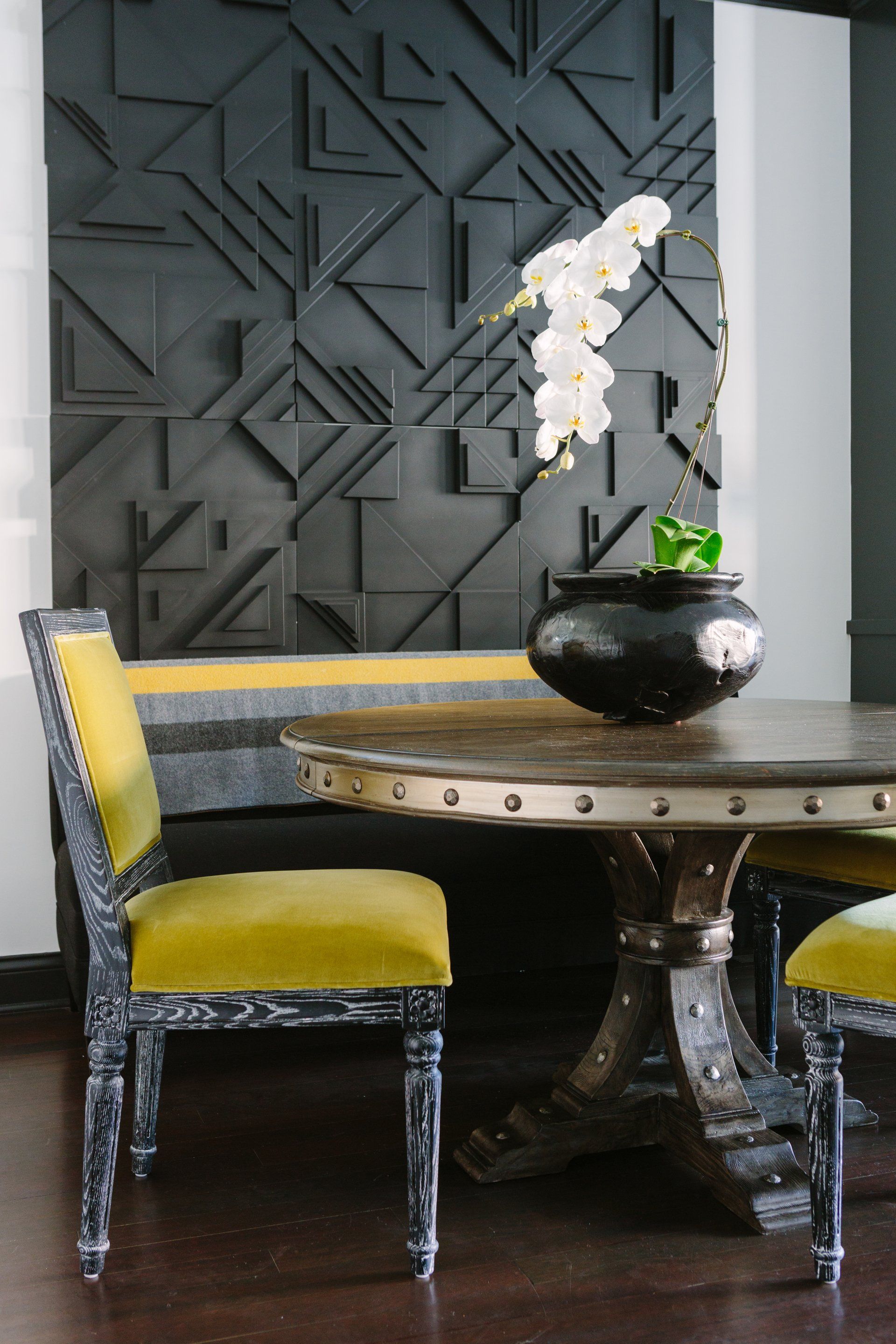 A table with a vase of flowers on it in front of a black wall
