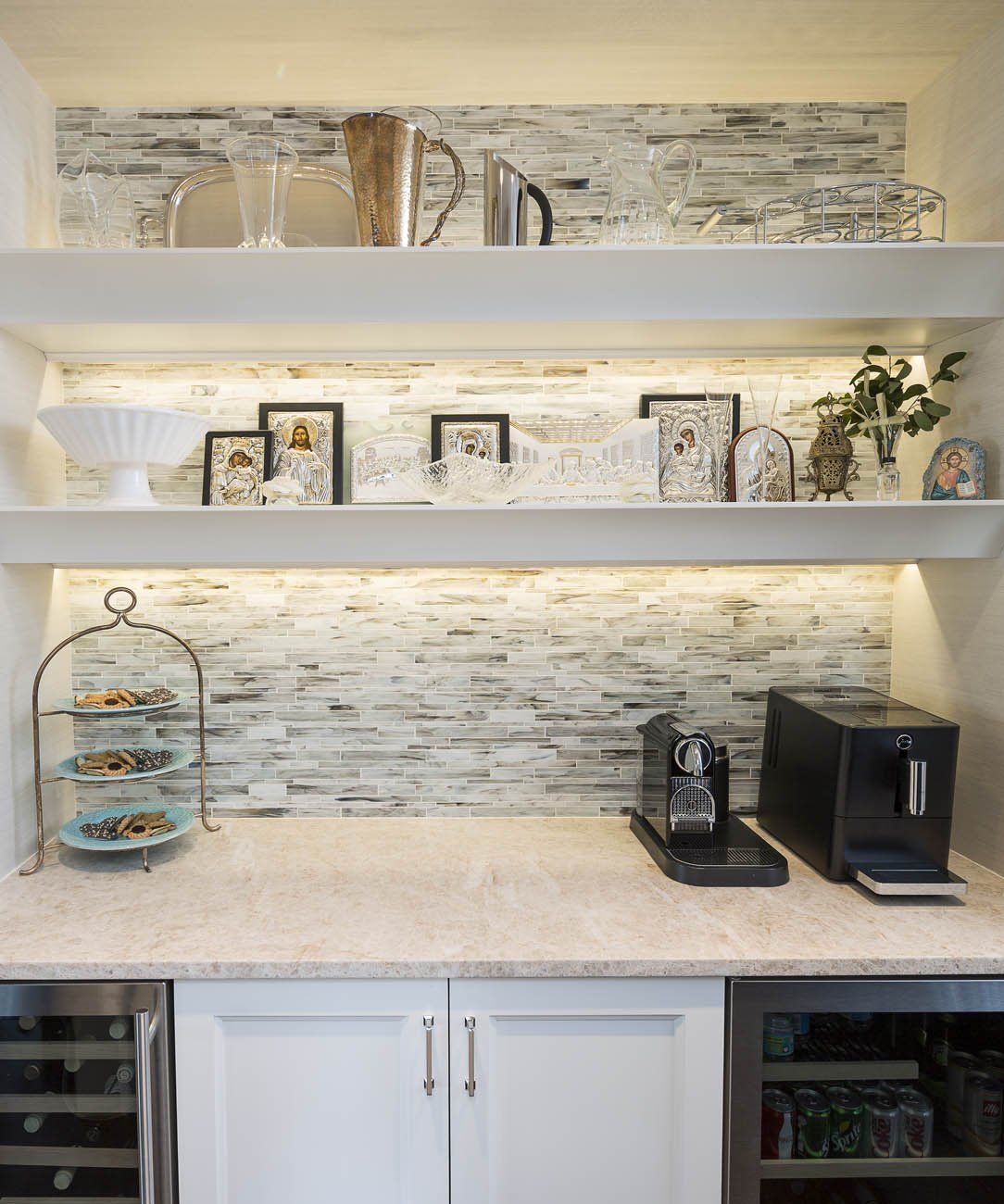 A kitchen with white cabinets , a wine cooler , a coffee maker , and shelves.