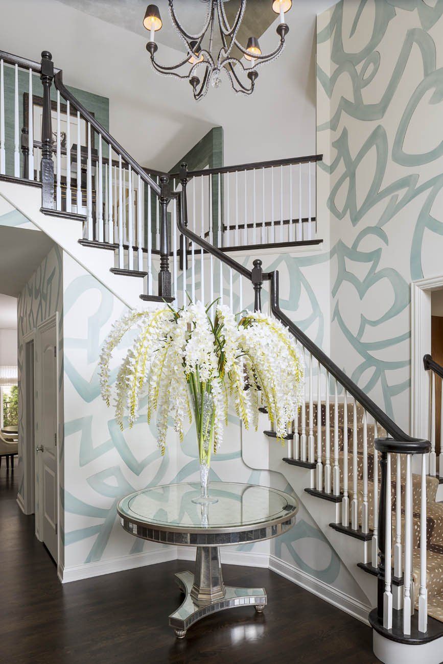 A vase of white flowers sits on a table in front of a staircase.