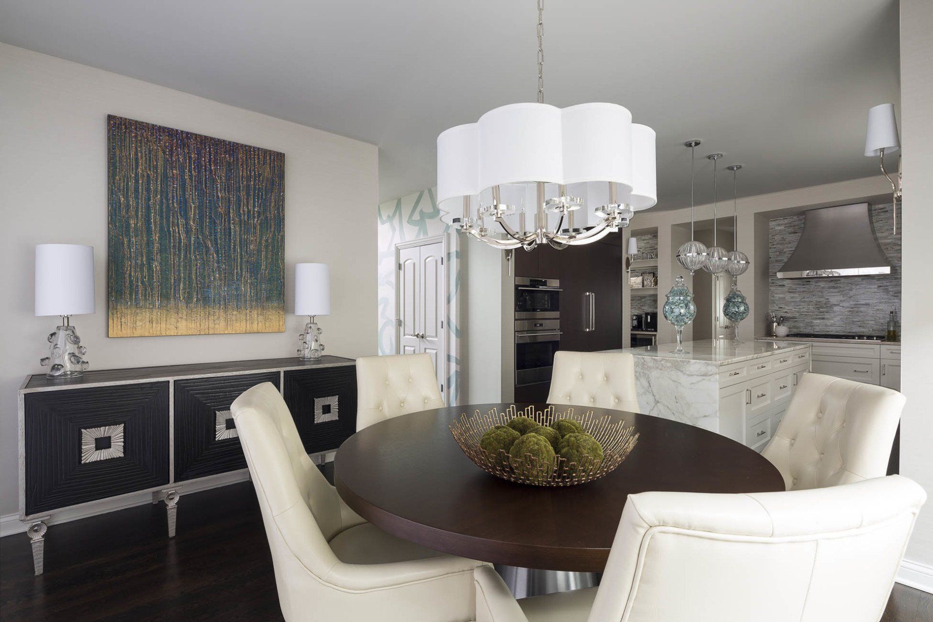 A dining room with a round table and white chairs