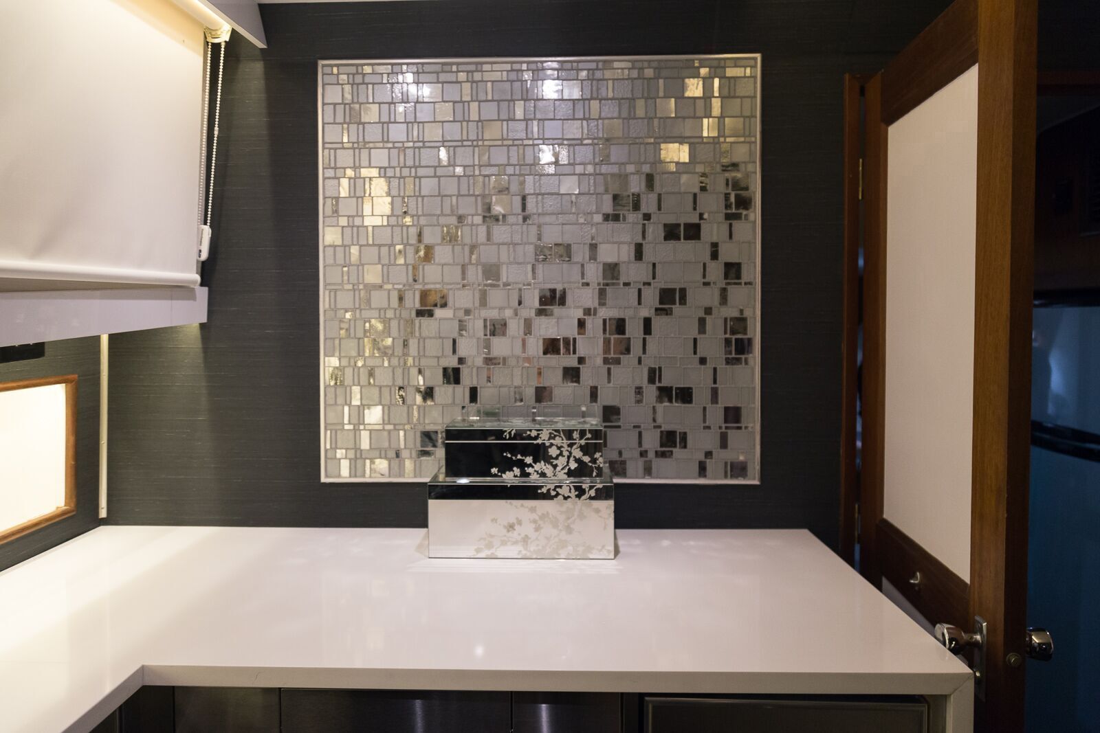 A kitchen with a mirrored wall and a white counter top