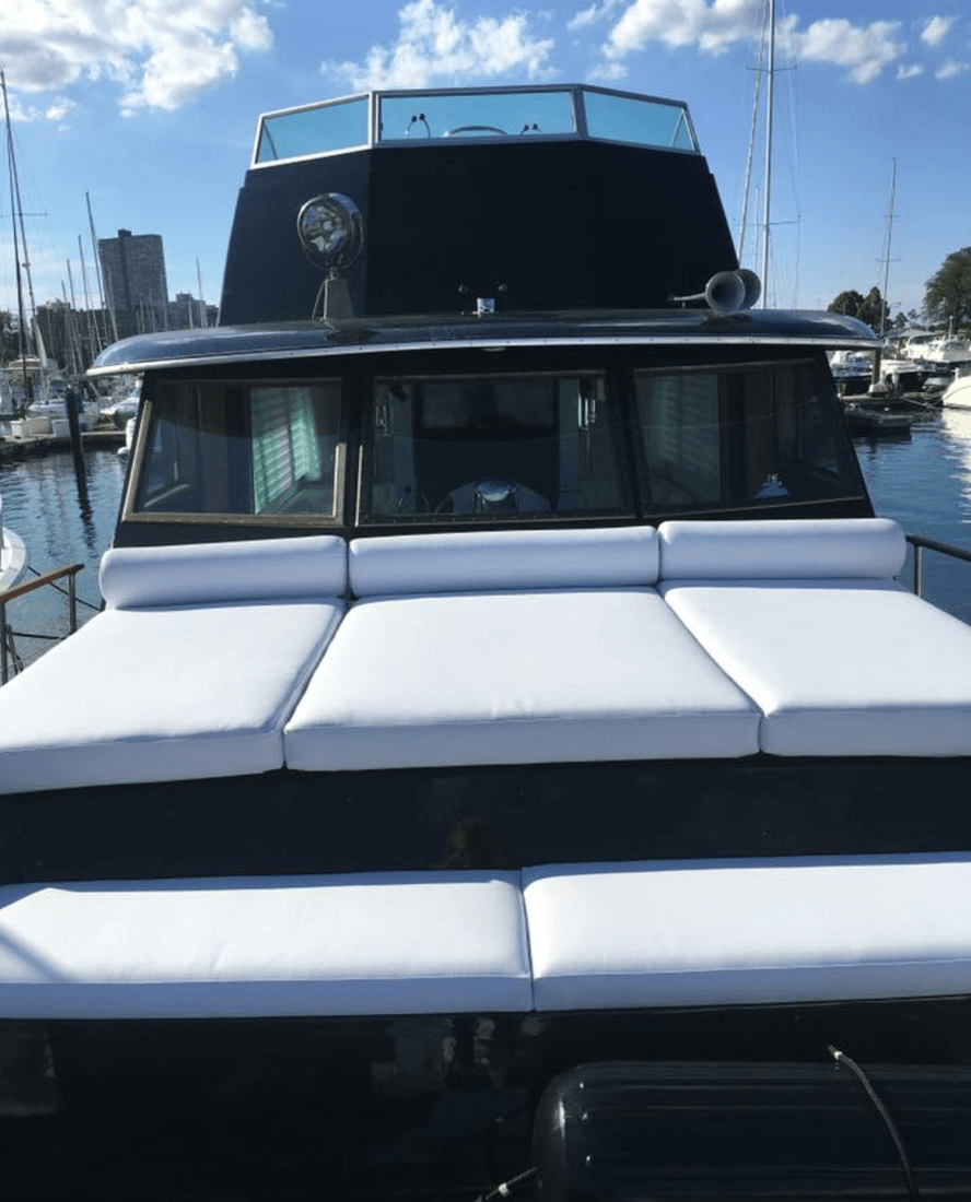 The front of a boat with white cushions on it