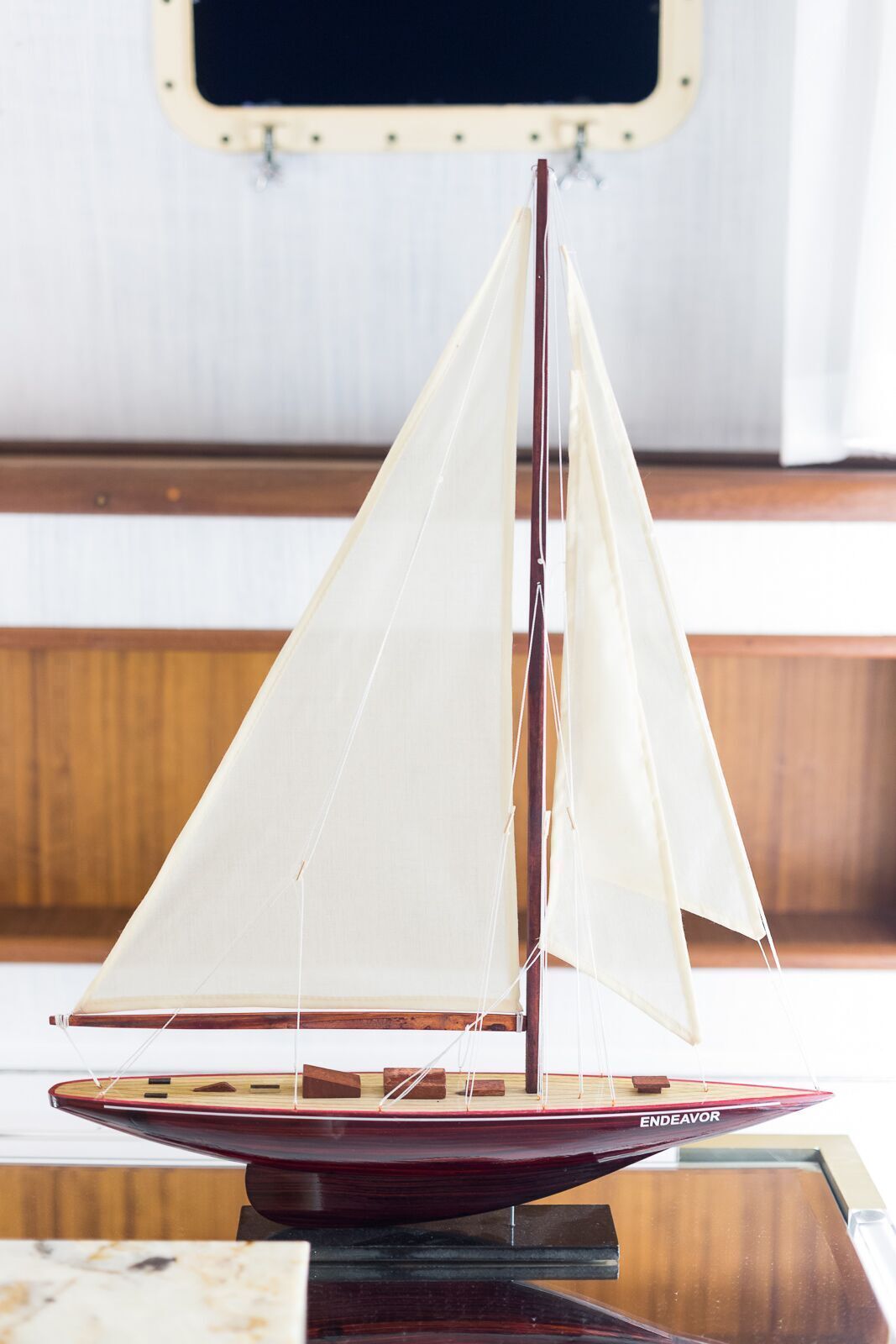 A small model sailboat is sitting on a glass table.