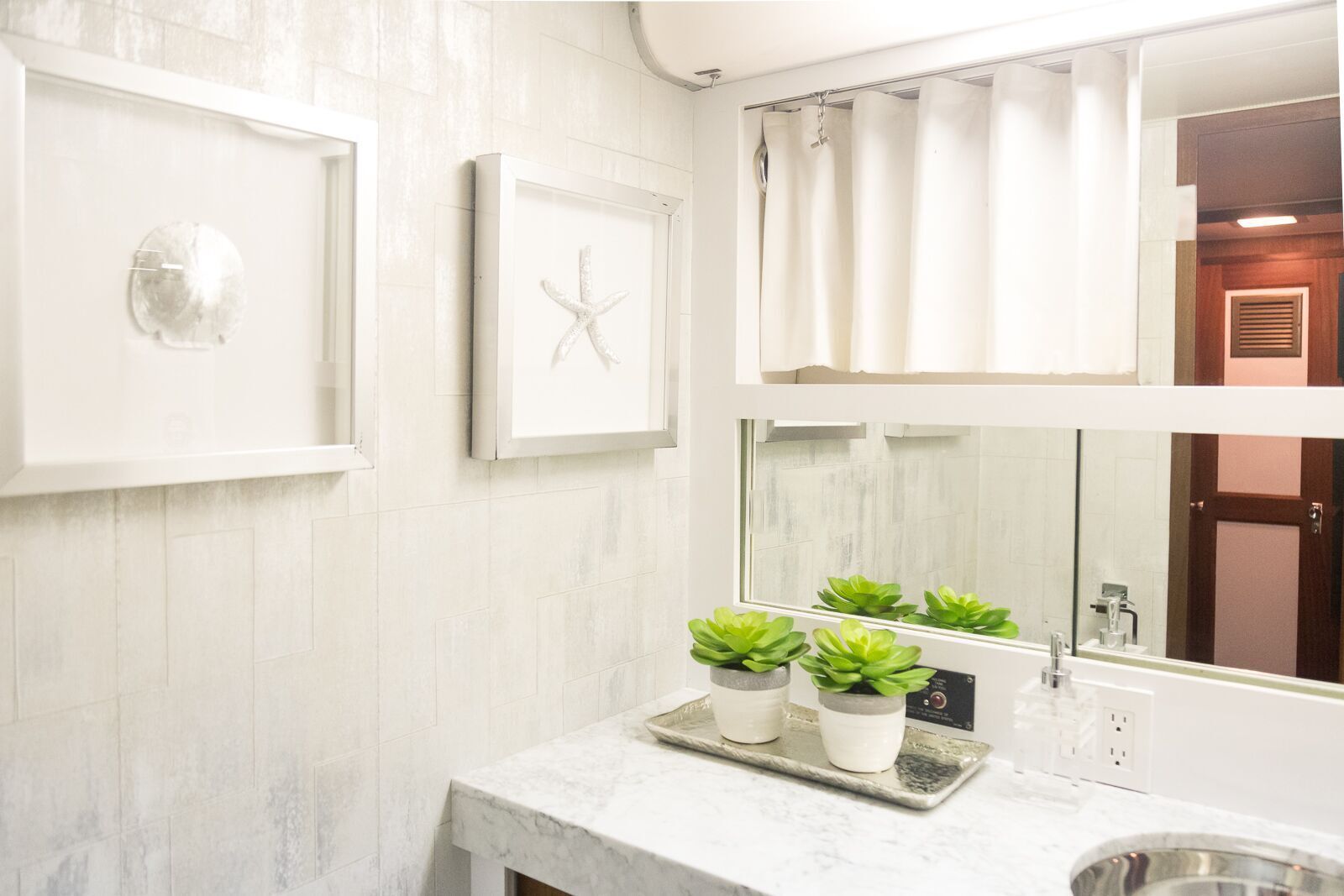 A bathroom with a sink , mirror , and potted plants.