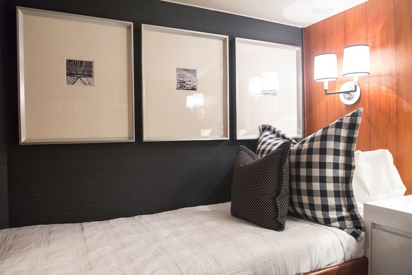 A bedroom with a bed , pillows and three paintings on the wall.