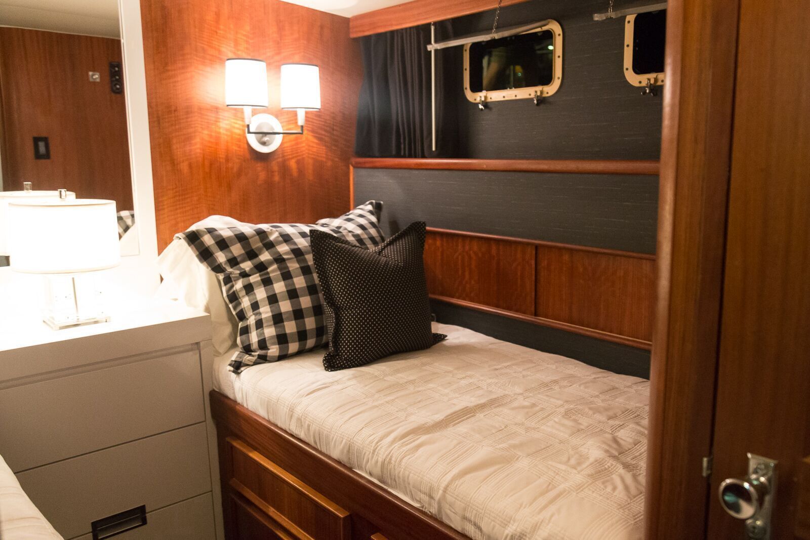 A bedroom on a boat with a bed and a mirror.