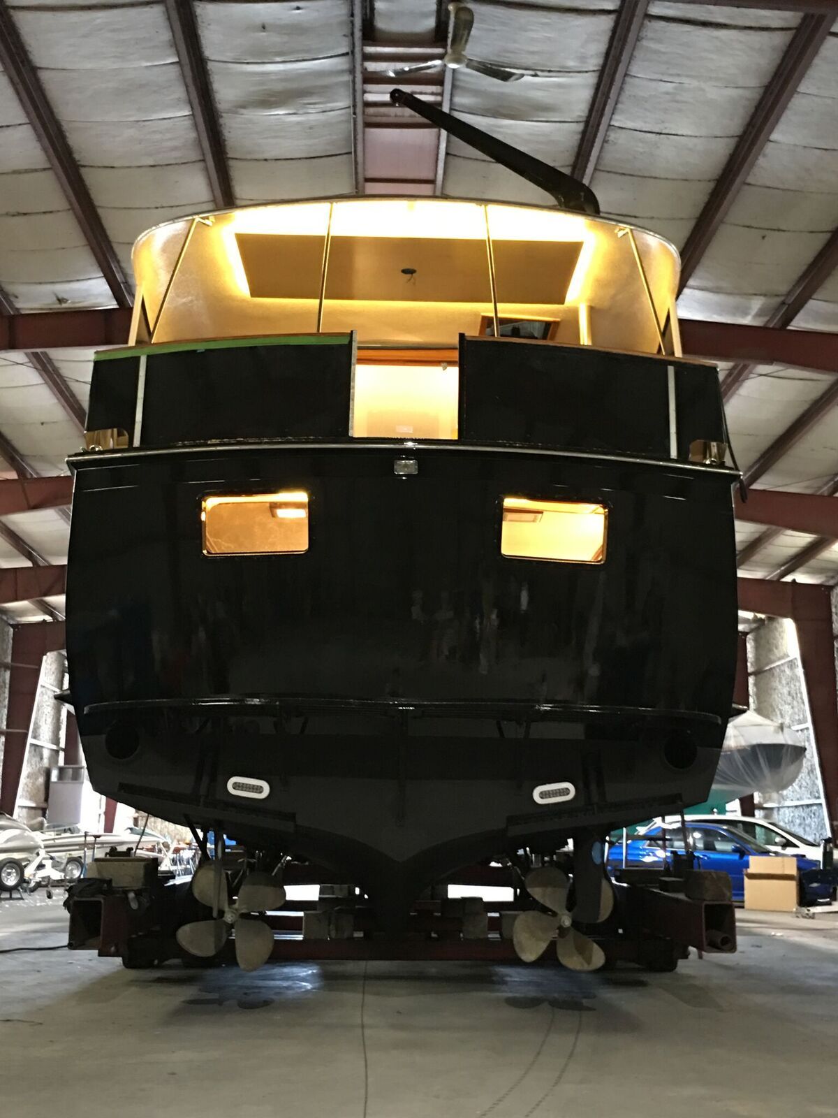 A large black boat is sitting in a warehouse