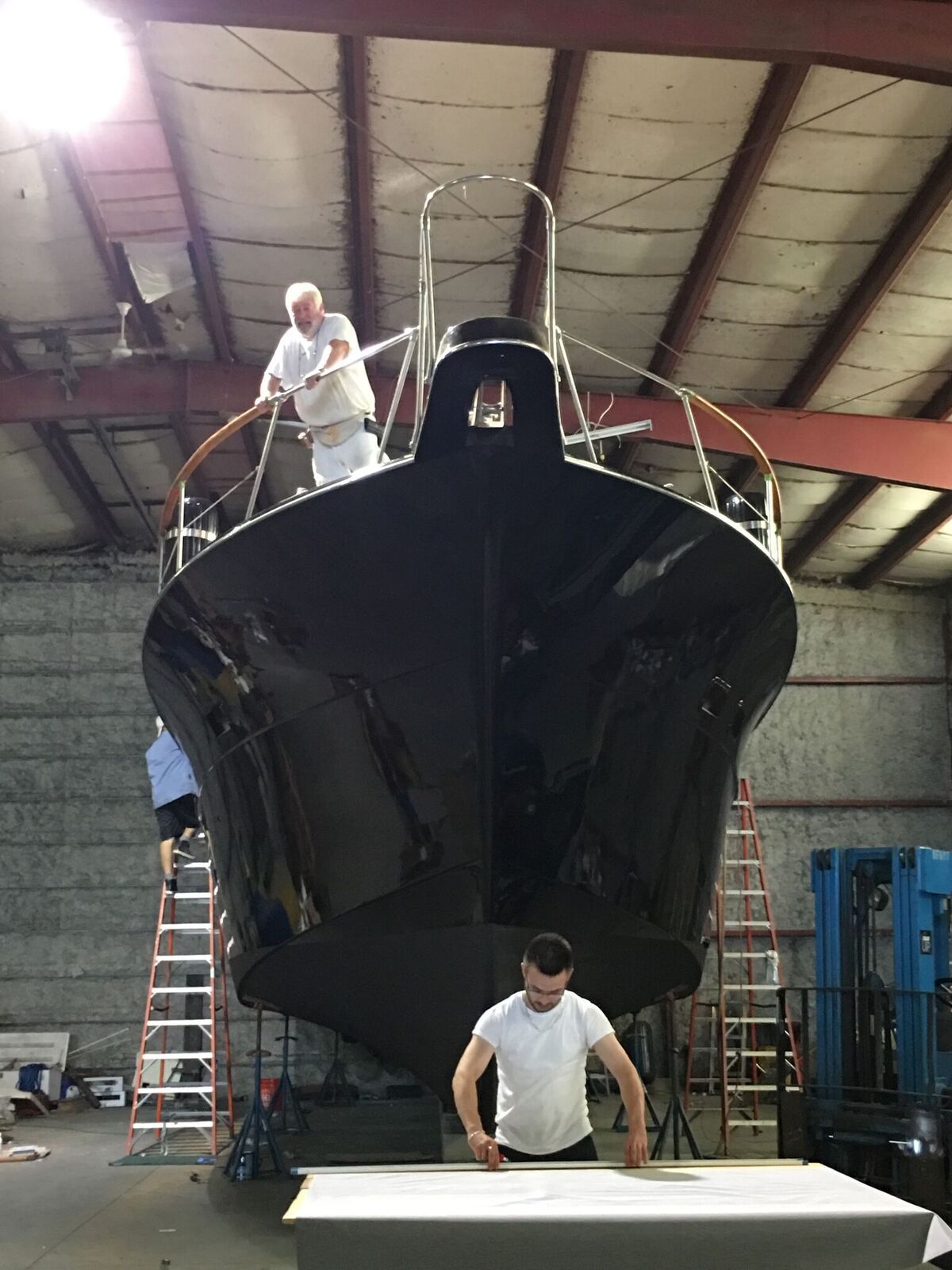 A man is standing in front of a boat in a warehouse.