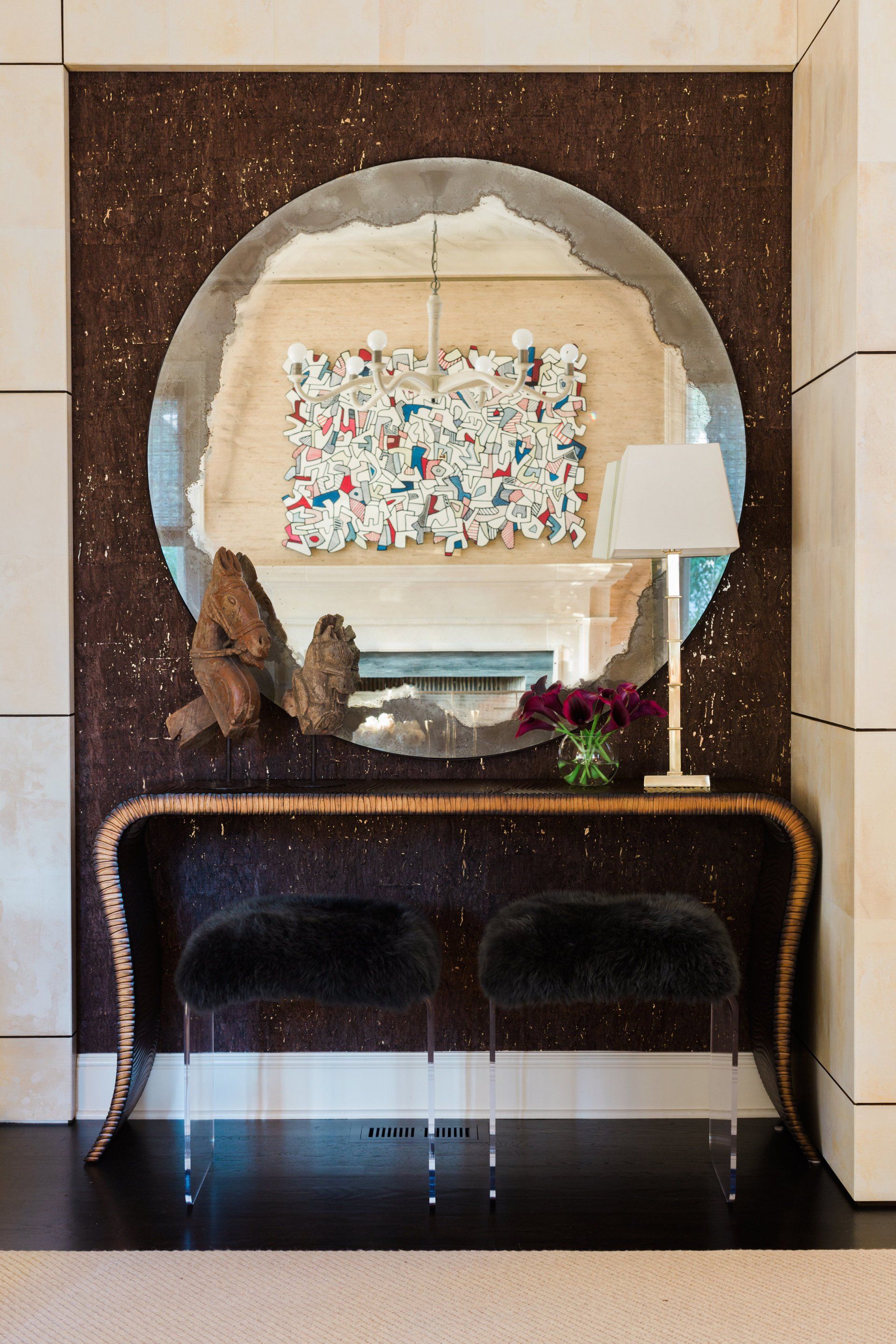 A round mirror is hanging on a wall above a table