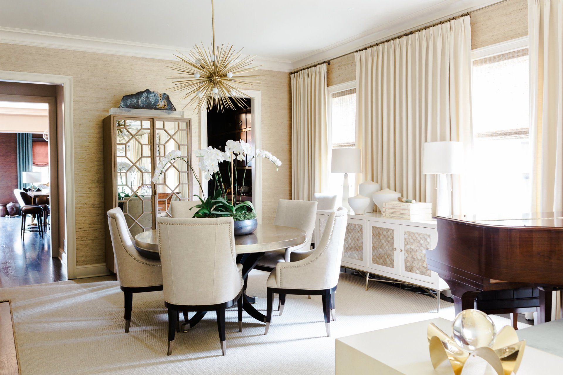 A dining room with a table and chairs and a piano.