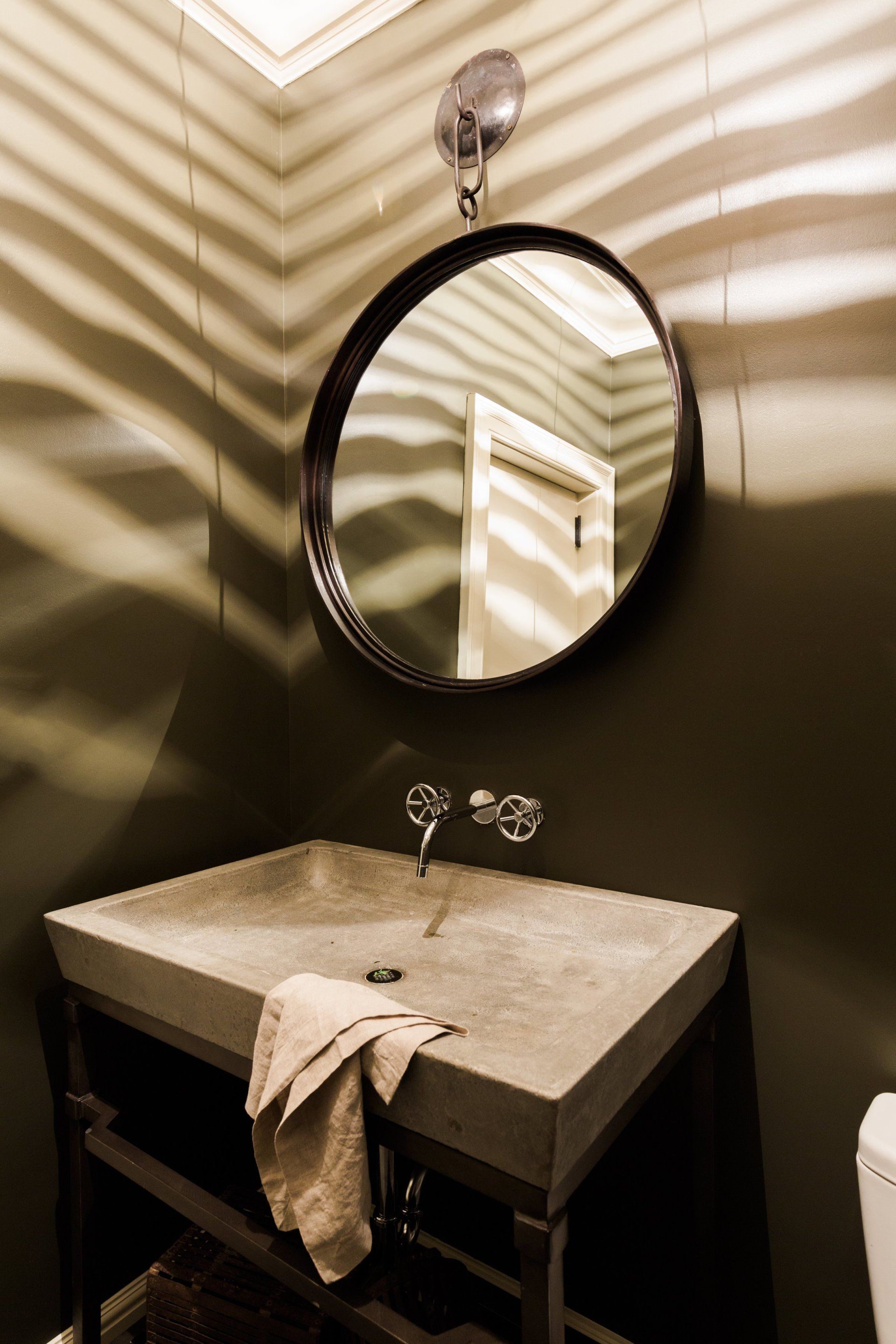 A bathroom with a round mirror above a sink