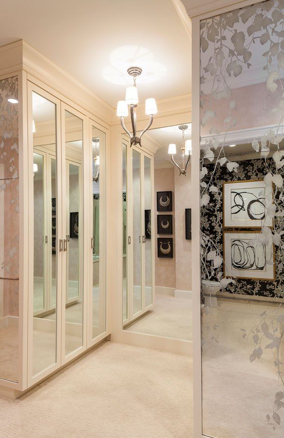 A walk in closet with lots of mirrors and pictures on the wall.