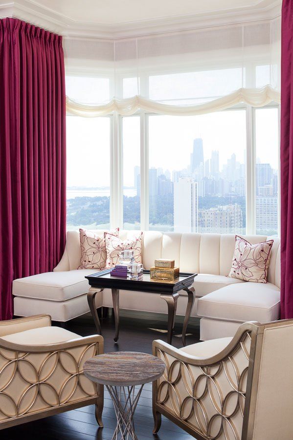 A living room with white furniture and purple curtains