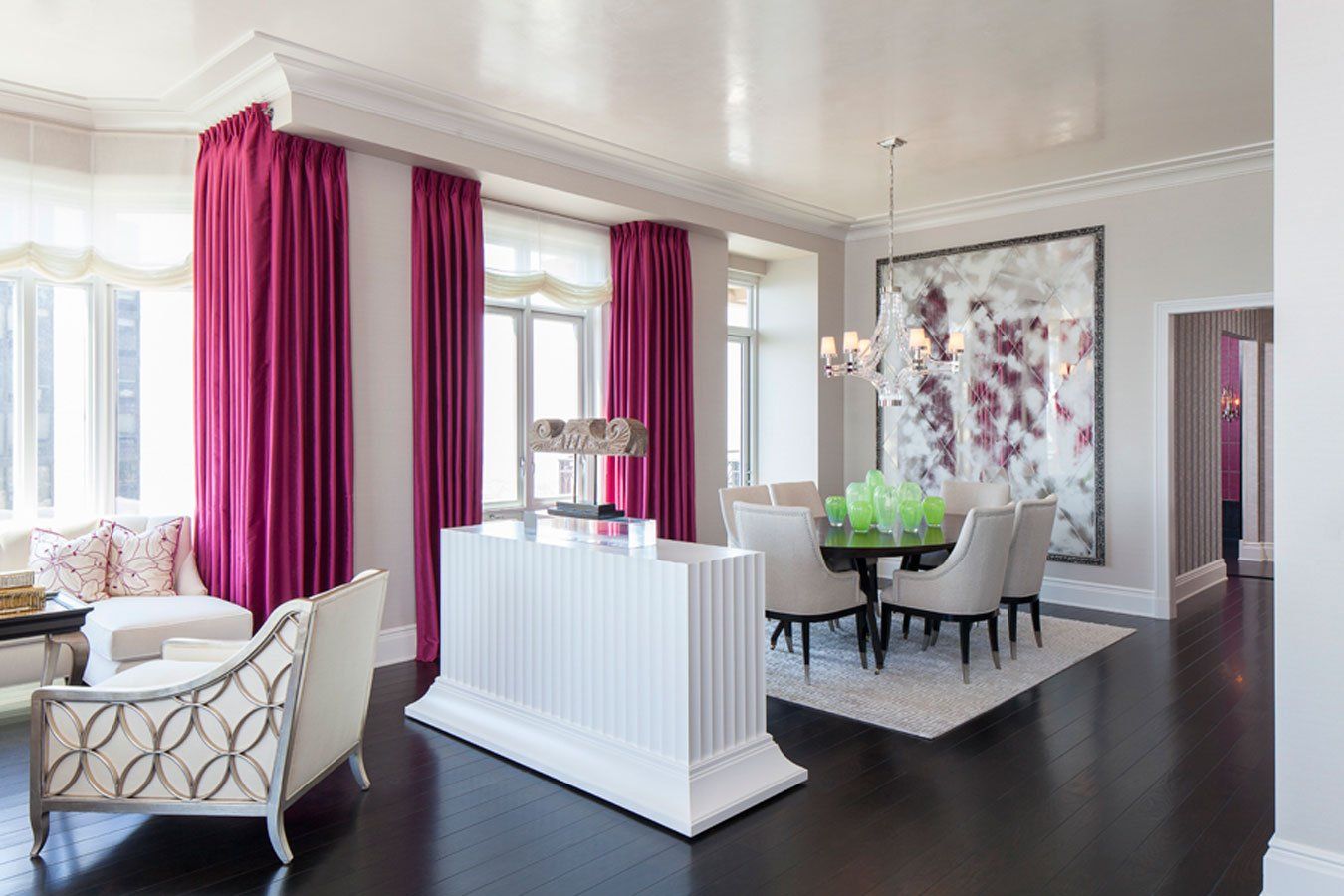 A living room with a dining room table and chairs and pink curtains.