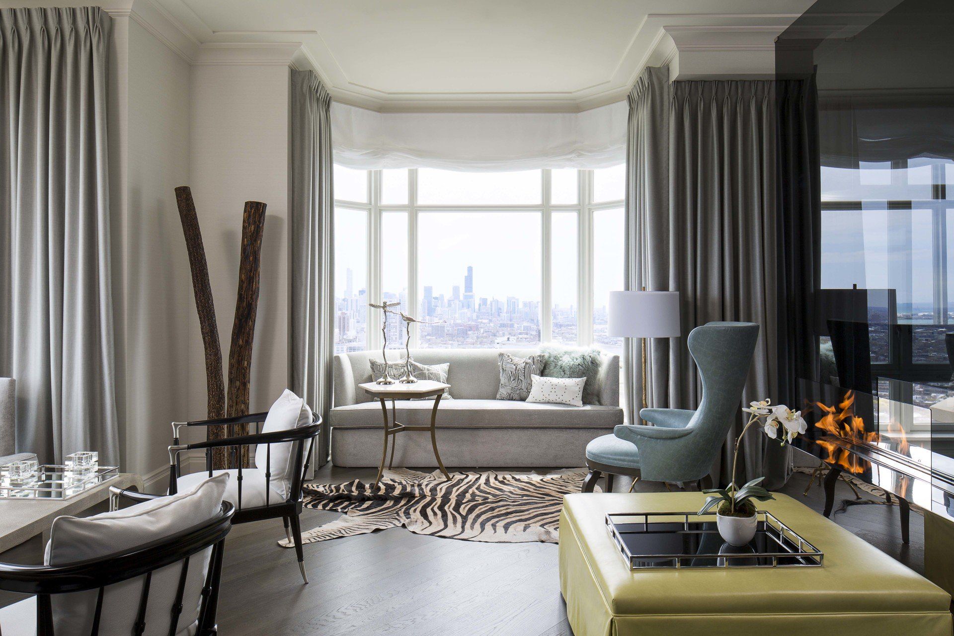 A living room with a couch , chairs , and a yellow ottoman