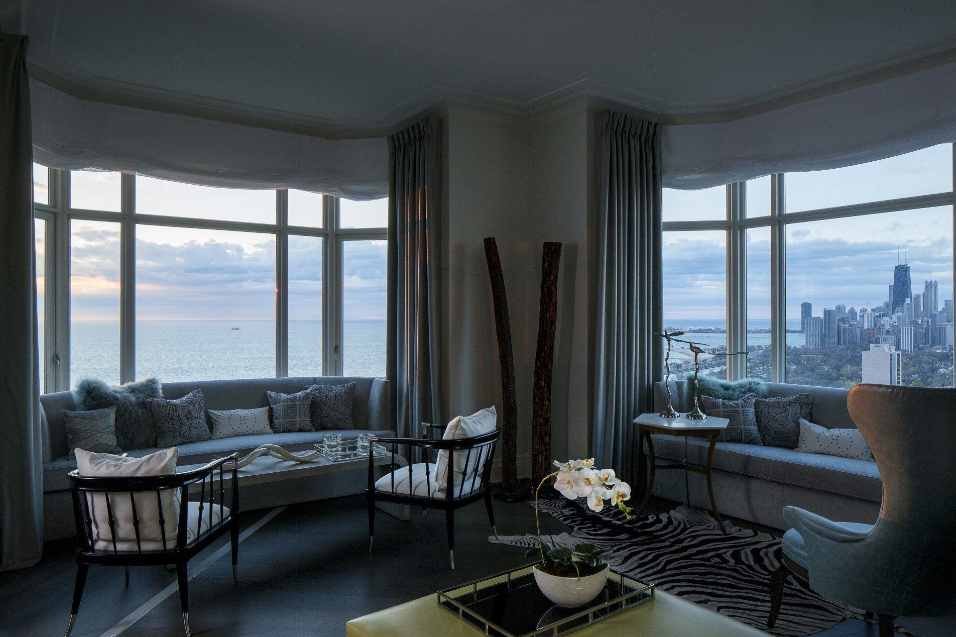 A living room with a couch , chairs , and a table with a view of the ocean.