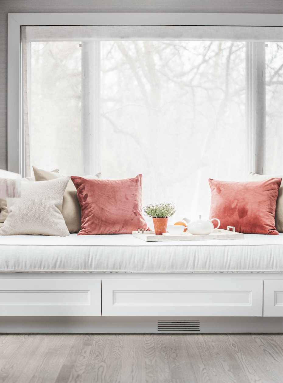 A window seat with pillows and a tray on it in a living room.