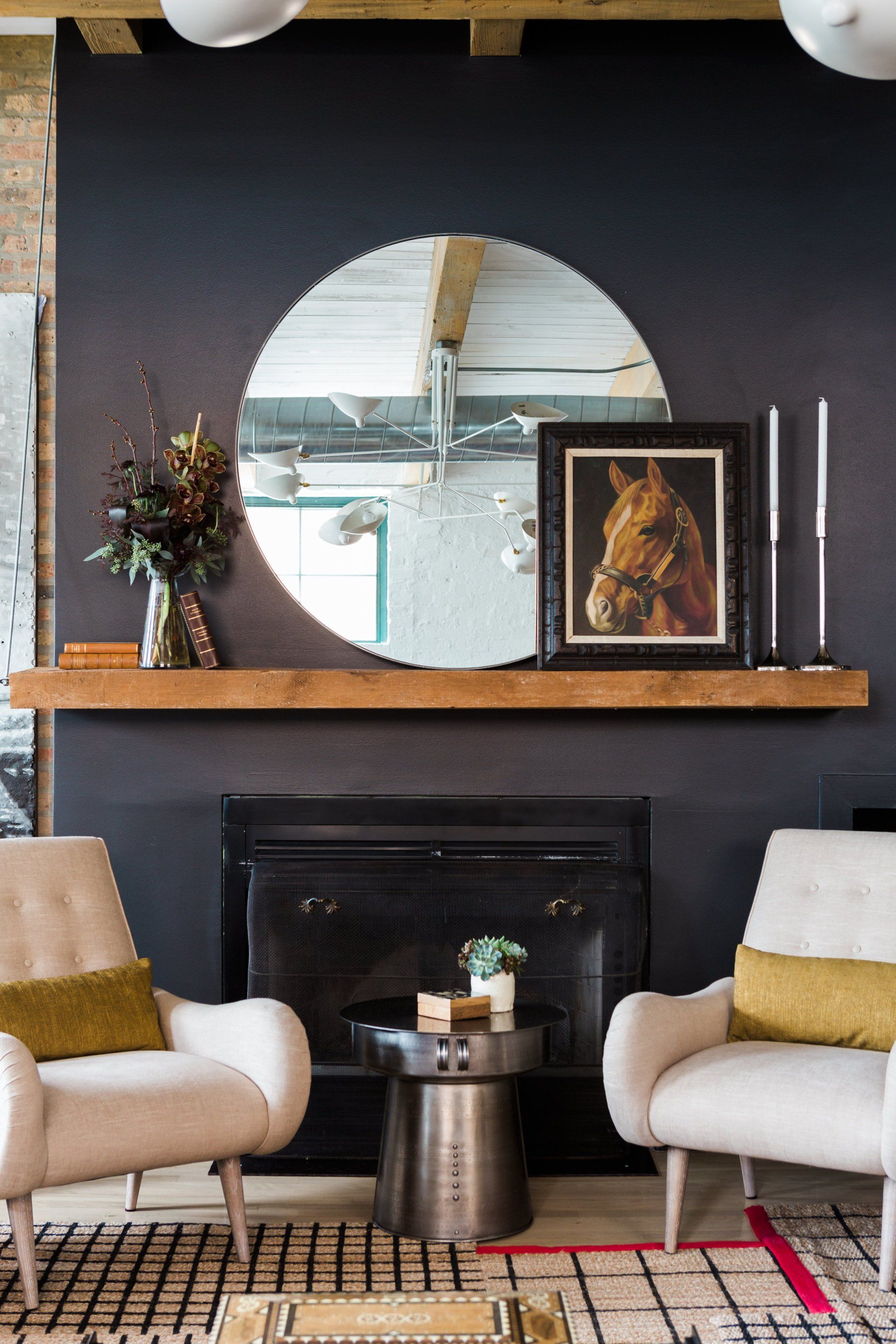 A living room with two chairs and a fireplace with a horse painting on the mantle.