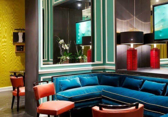 A living room with a blue couch and red chairs