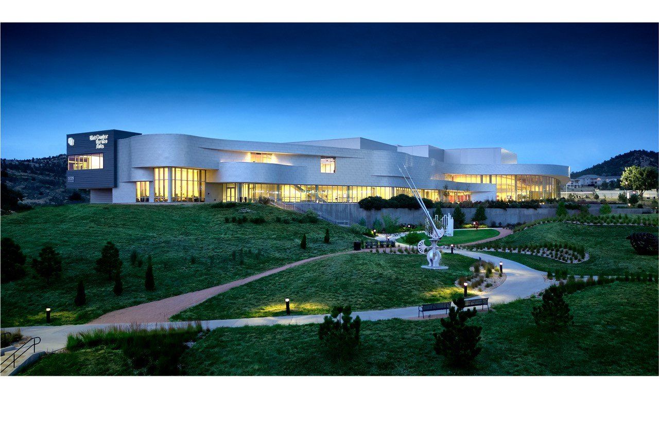 Modern art museum at dusk, with curved architecture, pathways, and illuminated windows.