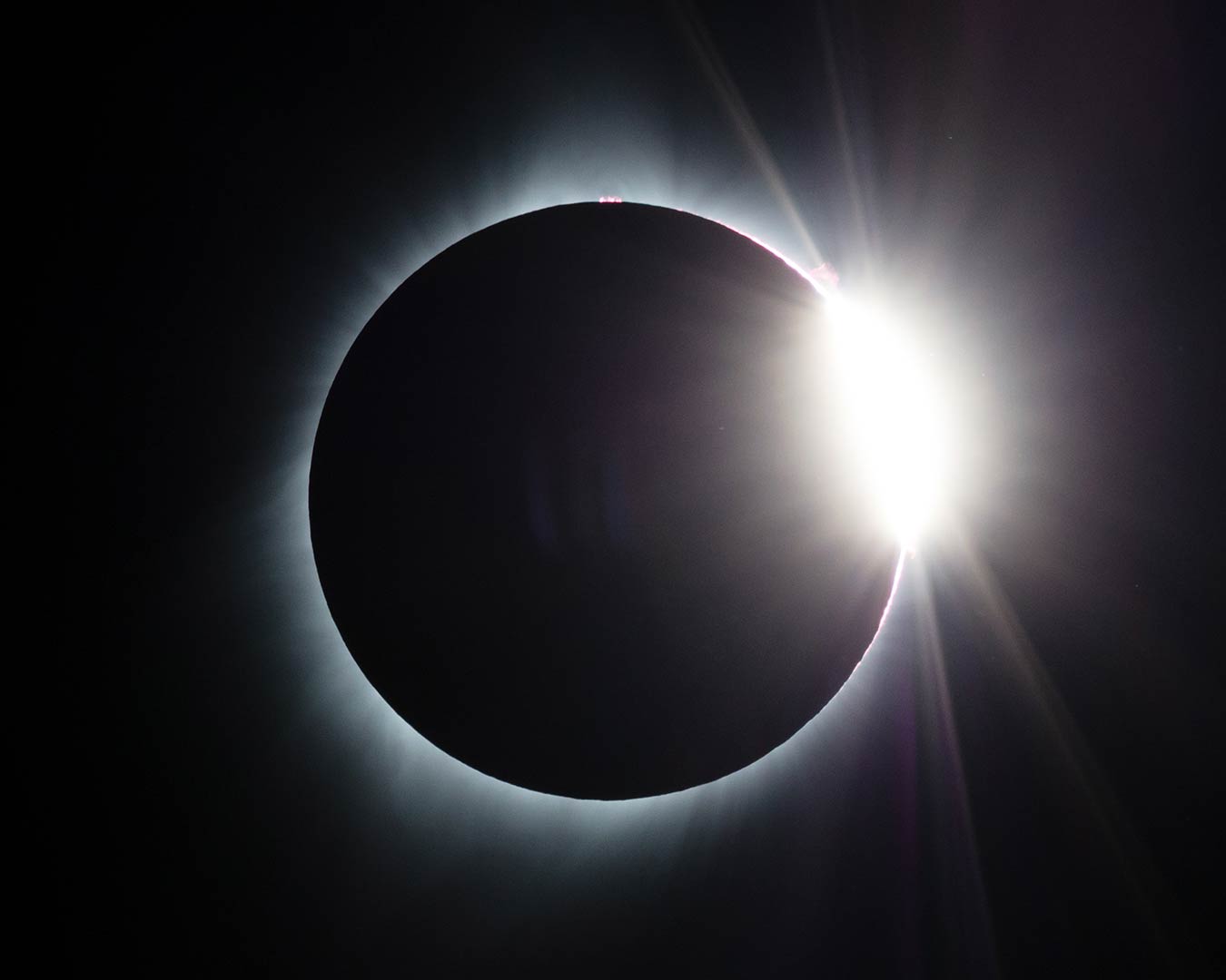 Solar eclipse: dark moon silhouetted against a bright, corona-like halo of light.