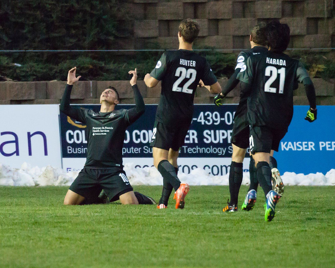 Action photo of Soccer players celebrating on a green field. 