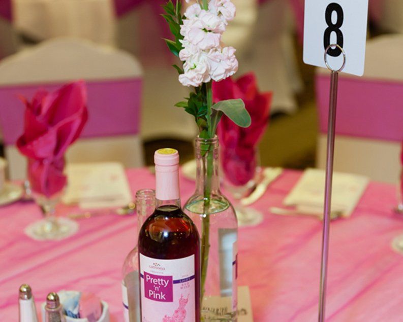 Pink table setting with wine, flowers, and a table number.