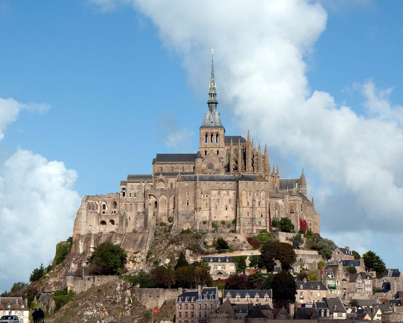 Mont Saint-Michel, France: Medieval abbey atop a rocky tidal island, under blue sky with clouds.